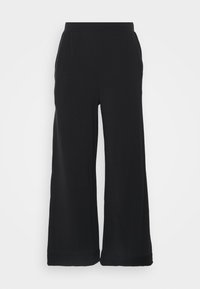 Svarta vida byxor i mjukt material, med elastisk midja och avslappnad passform. Både nederkant har en subtil manschettdetalj.