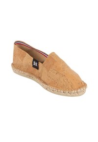 Chaussure à enfiler en liège avec un bout arrondi, couleur naturelle beige, semelle en jute tissée et doublure intérieure contrastante avec des accents rouges et bleus.