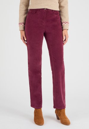 Pantaloni in velluto a coste bordeaux con gamba dritta, due tasche frontali e chiusura con bottone. Abbinati a stivaletti marroni.