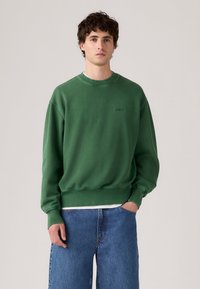 Groene katoenen sweatshirt met een ronde hals, geribbelde manchetten en zoom. Bevat een klein, ton sur ton Levi's logo op de borst. Gemaakt in combinatie met blauwe denim shorts.