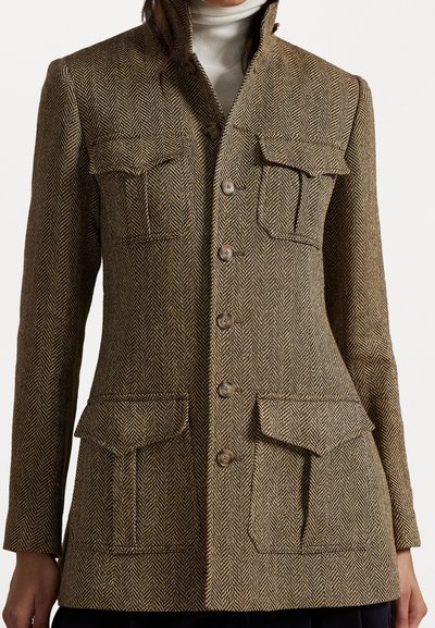 Sako s houndstooth vzorem v hnědé a béžové barvě. Obsahuje dvě náprsní kapsy, čtyři knoflíky a vysoký límec. Vyrobeno z texturované látky.