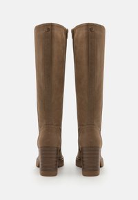 Bottes en cuir brun montant jusqu'au genou avec une finition texturée, fermeture éclair et un talon carré présentant des rainures horizontales.