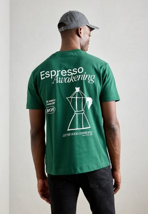 Groene katoenen T-shirt met witte tekst: "Espresso Awakening" en een afbeelding van een koffiezetapparaat. Korte mouwen en een relaxte pasvorm.