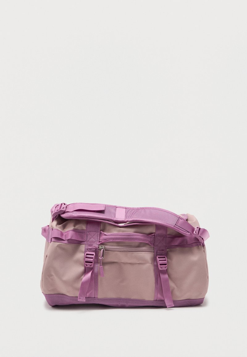 Τσαντάκι duffel σε ανοιχτό ροζ και λεβάντα με ρυθμιζόμενο ιμάντα ώμου, μπροστινή τσέπη με φερμουάρ και κλεισίματα με αγκράφα σε απλό λευκό φόντο.