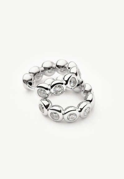 Δύο ασημένια δαχτυλίδια με ομοιόμορφα διατεταγμένους στρογγυλούς διαυγείς πολύτιμους λίθους τοποθετημένους σε γυαλιστερές βάσεις σε λευκό φόντο.