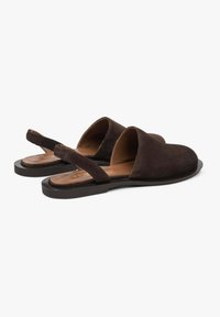 Bruine suède open-toe schoenen met een platte zool, voorzien van zijsnijdingen en een achterstrap voor een veilige pasvorm. Gladde textuur en eenvoudig ontwerp.