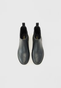 Čierne chelsea čižmy vyrobené z hladkej kože, s brogue detailmi, elastickými bočnými panelmi a úchytkami pre jednoduchéobúvanie.
