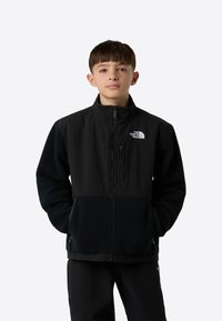 Crna jakna na patent s flis tijelom i najlonskim rukavima, s visokim ovratnikom i logotipom The North Face na prsima.