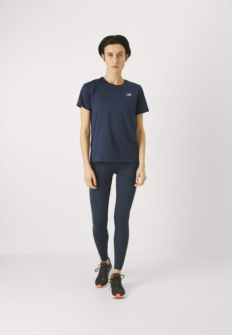 T-shirt de sport marine à manches courtes, associé à des leggings ajustés assortis. Des chaussures de course noires avec des accents orange complètent la tenue.
