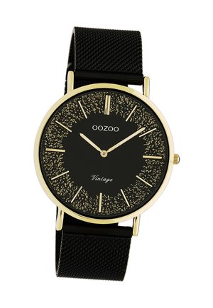 Black mesh band watch with a round gold-tone case, black dial, gold hour markers, and textured glitter detail. Features quartz movement.