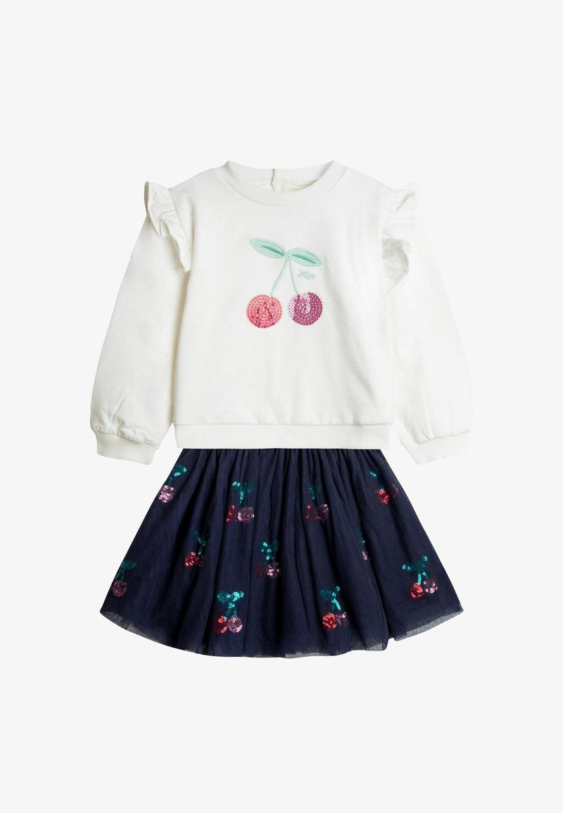 Fehér pulóver fodros ujjakkal és cseresznye hímzéssel, navy tüll szoknyával párosítva, amelyen flitteres cseresznyék és levelek találhatók.