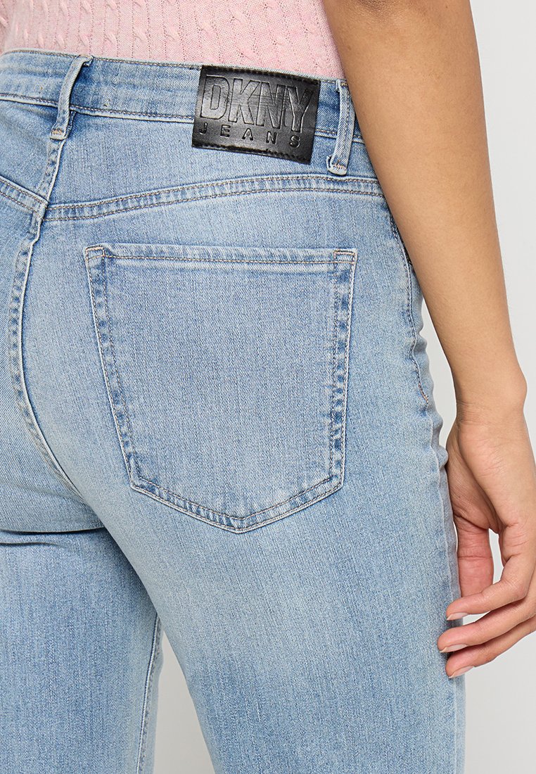 Jasnoniebieskie dżinsy o dopasowanym kroju, z czarną skórzaną metką DKNY z tyłu przy pasie i dwoma tylnymi kieszeniami.
