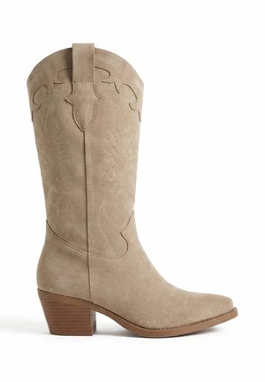 Botte de cowboy beige en daim mi-mollet avec des coutures décoratives, un bout pointu et un talon bloc empilé.
