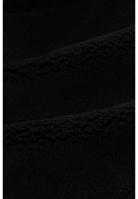 Črna flisna tkanina z mehkobo in teksturiranim površjem. Na robovih vsebuje subtilne šive. Gladek in topel videz.