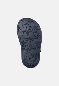 Marinsvart gummisula med en lekfull, präglad illustration av djur, inklusive hundar och fåglar, där ordet "CAMPER" står i fokus.