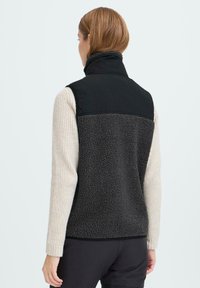 Schwarwest und graue Fleece-Weste mit hohem Kragen. Die Rückseite besteht aus einem strukturierten Fleece-Material mit einem glatten, schwarzen Panel oben.