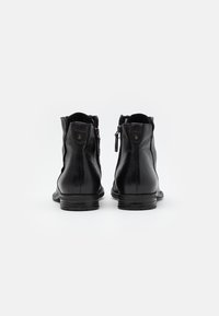 Černé kotníkové kožené boty s hladkým povrchem, kulatou špičkou a bočními zipy, s nízkým blokovým podpatkem a minimálním zdobením.