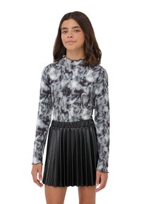 Maglia a maniche lunghe e collo alto in fantasia marmorizzata grigia e nera, abbinata a una gonna plissettata in ecopelle nera con vita elastica.