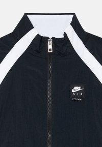 Nike Air striukė su aukšta apykakle, priekiu užtraukiama ir kontrastingais baltais šonais. Pagaminta iš lengvos audinio tamsiai mėlynos spalvos.