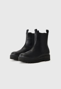 Mustad mustad musta nahast kingad elastsete külgpaneelidega, ümar varvas ja paks kummitald. Omab külgpaneelidel tõmbepliindreid, mis võimaldavad kingade mugavat selga panemist.