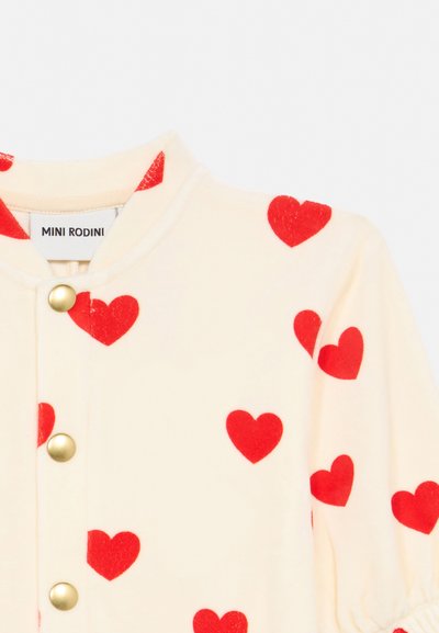 Κρεμένιο ρούχο με κόκκινες καρδιές, χρυσά κουμπιά ασφαλείας και στρογγυλή λαιμόκοψη με την ετικέτα "Mini Rodini".