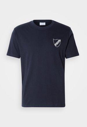 Navy blue cotton t-shirt with short sleeves, round neckline, and a white shield logo on the left chest featuring the text "Les Deux."