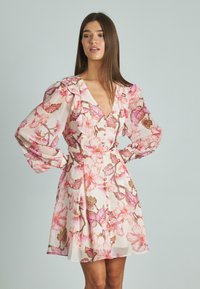 Vestido floral con escote en V, mangas abullonadas y cintura ajustada. Fabricado en una tela ligera con un patrón de flores en tonos rosa y verde.