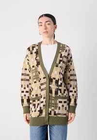 Trikotāžas kardigans ar V veida kaklu, zaļiem akcentiem un pogu aizdari, kas rotāts ar ģeometrisku rakstu dzeltenā, brūnā un krēmīgā krāsā; divas priekšējās kabatas.