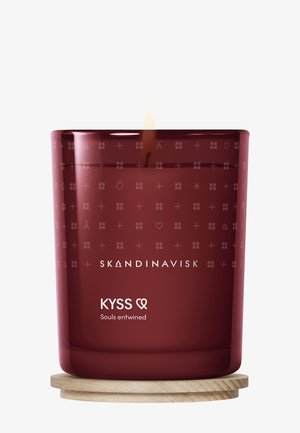 Pot à bougie en verre rouge avec une base en bois, présentant un motif en relief et un texte blanc indiquant "SKANDINAVISK KYSS Âmes entremêlées."