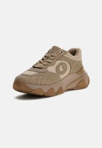 Beige ja tumepruun paksu taldaga treeningking, millel on võrgust ja nahast detailid, pealelõikega kinnitamine, ribisool ja külje peal ümmargune logo.