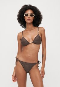 Brown ribbed bikini with triangular top and adjustable tie-side bottoms. Features decorative beads on straps. Smooth texture.