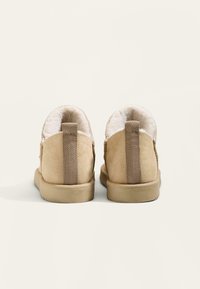 Beżowe zamszowe botki za kostkę z miękkim, puszystym wykończeniem, z solidnym uchwytem na pięcie i gumową podeszwą. Teksturowana powierzchnia z detalami szycia.