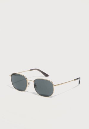 Lunettes de soleil avec monture en métal doré, verres rectangulaires foncés et branches noires, présentées en angle sur une surface blanche.