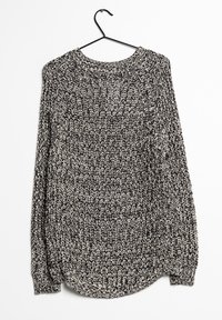 Strickpullover in Schwarz und Weiß, mit rundem Ausschnitt, langen Ärmeln und einem strukturierten Muster. Hängt an einem schwarzen Haken.