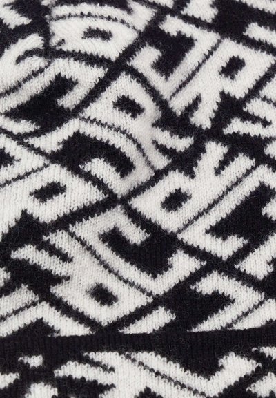 Tessuto a maglia a righe bianche e nere con forme geometriche e lettere, dall'aspetto morbido e texture. 