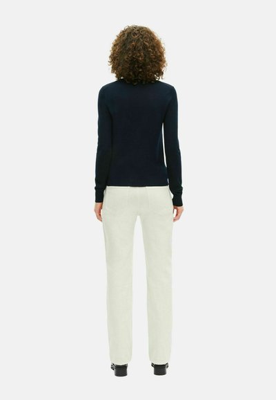 Maglione navy a maniche lunghe, abbinato a pantaloni color crema. Tessuto morbido, vestibilità slim e cuciture dettagliate sui pantaloni.