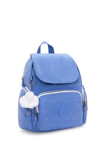 Modrý nylonový batoh s klopovým uzávěrem, přední kapsou na zip, bílými zipovými detaily a připevněným chlupatým klíčenkou. Zaoblený tvar.