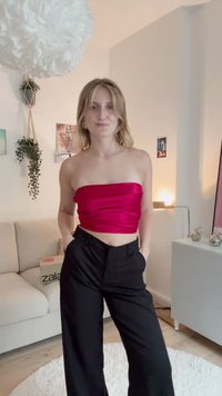 Top ajustado y sin tirantes en satén magenta brillante, combinado con pantalones de pierna ancha negros de talle alto, con bolsillos laterales y un diseño elegante.