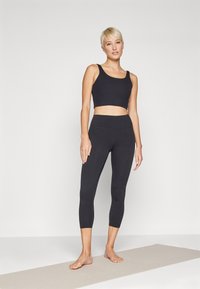 Top cropped preto e leggings de cintura alta feitas de material elástico, com uma textura suave e um design ajustado ao corpo.