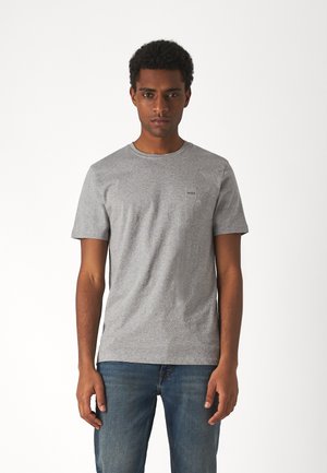 Gray cotton T-shirt with a round neck, short sleeves, and a small logo patch on the chest. Paired with blue denim jeans.