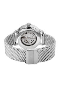 Montre en acier inoxydable argenté avec un bracelet en maille, boîtier arrière transparent montrant un mouvement mécanique complexe, et une couronne pour ajuster l'heure.