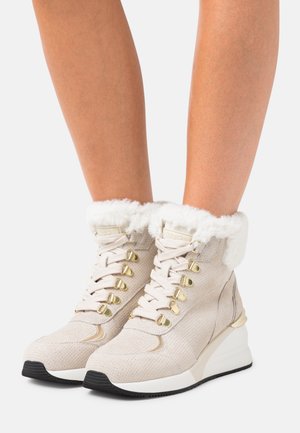 Beżowe buty high-top o teksturowanym wykończeniu, złotym okuciu i białym kołnierzu z sztucznego futra, z podeszwą na koturnie i eleganckim designem.