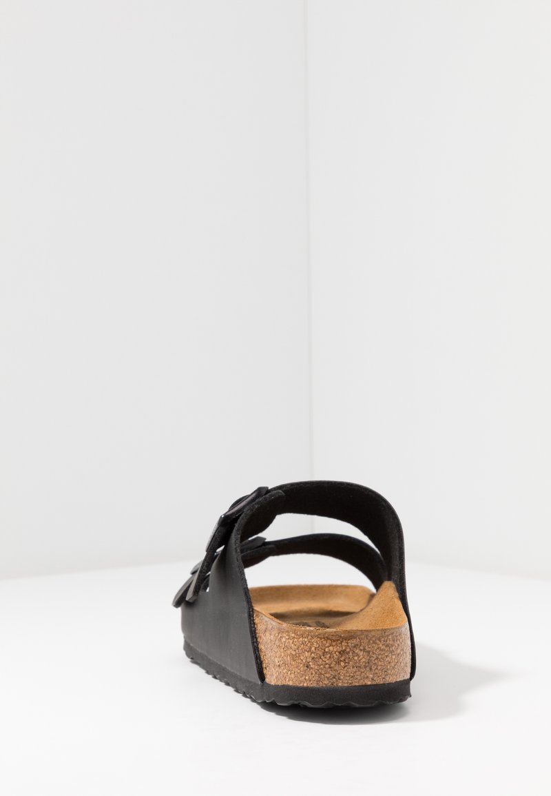Black open-back sandal featuring a cork footbed, smooth material, and adjustable straps with a sturdy sole. Minimalist design with a clean finish.