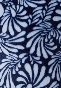 Tessuto blu navy con motivo floreale bianco che presenta foglie avvolgenti. Texture morbida con motivi dettagliati e ripetuti, creando un effetto visivo dinamico.