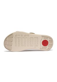 Crèmekleurige sandaalzool met een geperst "fitflop"-logo, textuurpatronen voor grip en een rode cirkelvormige accent aan de hiel.