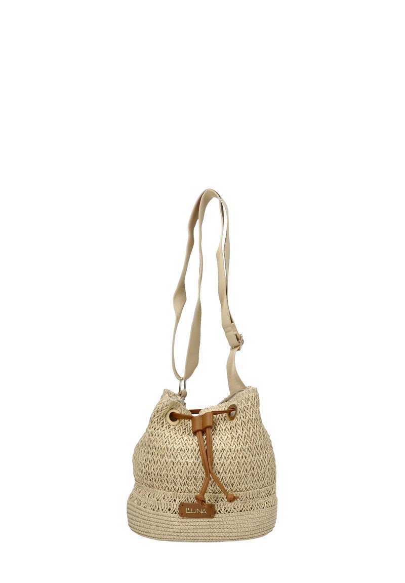 Bolso tipo cubo tejido en color beige con un acabado texturizado, cierre de cordón y correa de tela ajustable. Presenta un detalle de cuero en la base.