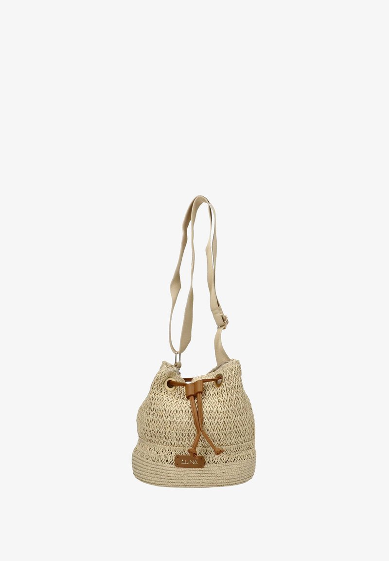 Bolso tipo cubo tejido en color beige con un acabado texturizado, cierre de cordón y correa de tela ajustable. Presenta un detalle de cuero en la base.