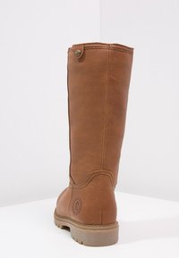 Hoge bruine leren laars met gestikt detail, ronde neus, robuuste zool en een kleine metalen knop dichtbij de bovenkant op een effen witte achtergrond.