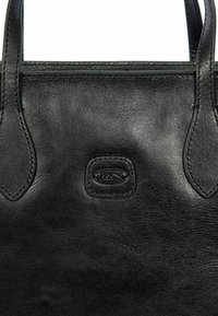 Borsa a tracolla in pelle nera, con una texture liscia, doppi manici superiori e un logo del marchio in rilievo sul davanti. Design classico con accenti minimi.