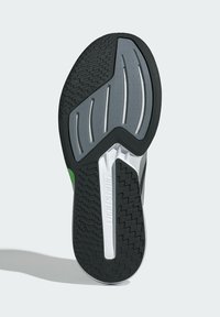 Čierna a šedá gumová podrážka topánky s textúrovaným dizajnom, s zeleným akcentom a kontrastnou bielou medzipodrážkou pre stabilitu.